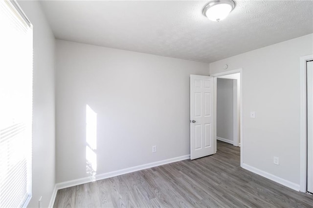 unfurnished room with wood finished floors, baseboards, and a textured ceiling