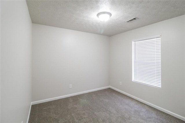 carpeted empty room with visible vents, baseboards, and a textured ceiling