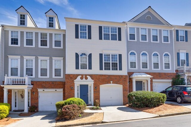 multi unit property featuring driveway, brick siding, and an attached garage