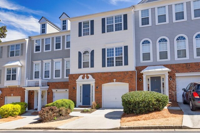 townhome / multi-family property with brick siding, an attached garage, and driveway