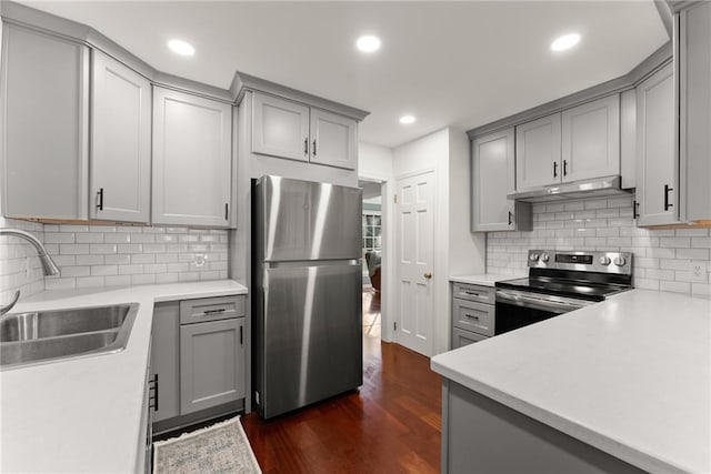 kitchen with gray cabinets, decorative backsplash, sink, dark wood-type flooring, and stainless steel appliances