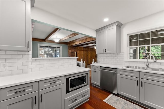 kitchen with dark hardwood / wood-style flooring, stainless steel appliances, sink, gray cabinetry, and beam ceiling