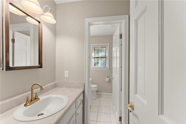 bathroom with toilet, vanity, and tile patterned flooring