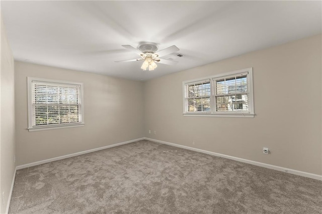 spare room with ceiling fan, a wealth of natural light, and light colored carpet