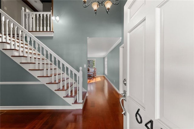 foyer entrance with wood-type flooring, crown molding, and a notable chandelier