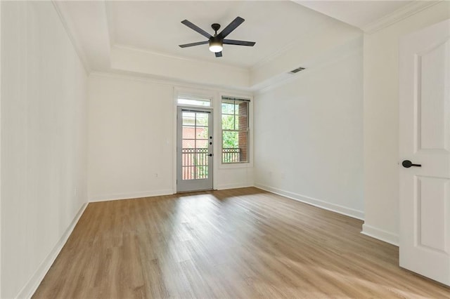 spare room featuring ceiling fan, a raised ceiling, light wood-type flooring, and ornamental molding