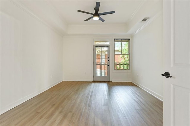 unfurnished room with a tray ceiling, ceiling fan, ornamental molding, and light wood-type flooring