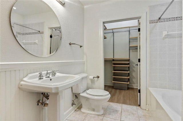 bathroom featuring tile patterned flooring, toilet, and tiled shower / bath