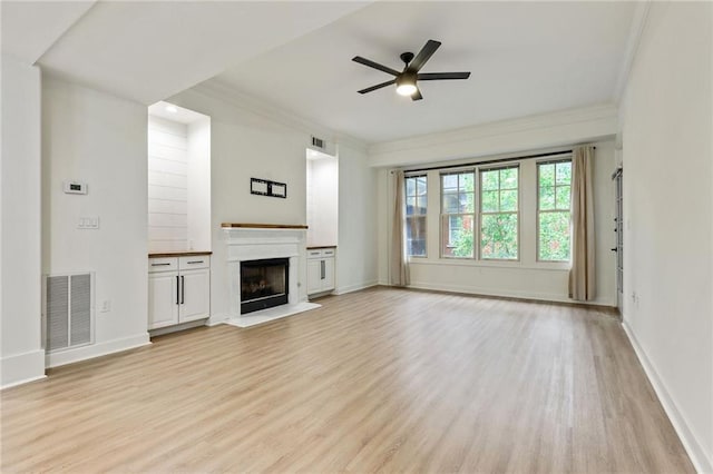 unfurnished living room featuring ceiling fan, crown molding, and light hardwood / wood-style flooring