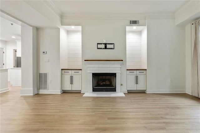 unfurnished living room with light wood-type flooring, a fireplace, and ornamental molding