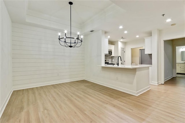 kitchen with light wood-type flooring, white cabinetry, kitchen peninsula, and appliances with stainless steel finishes