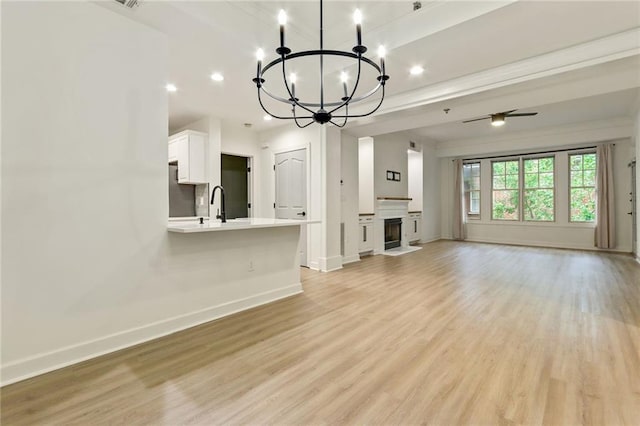 unfurnished living room featuring light hardwood / wood-style floors and ceiling fan with notable chandelier