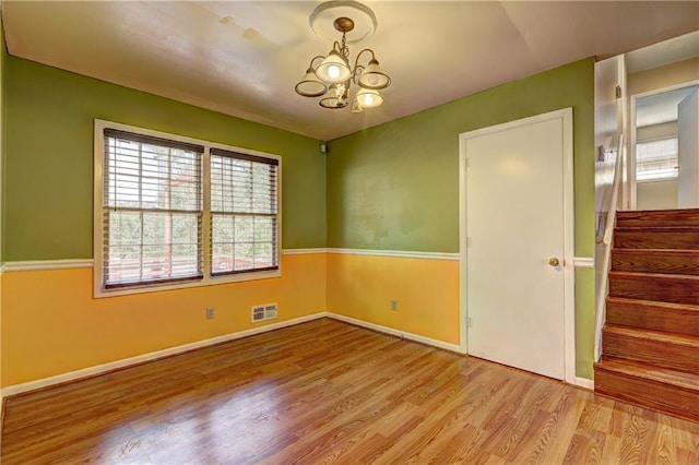 unfurnished room featuring a notable chandelier and light wood-type flooring