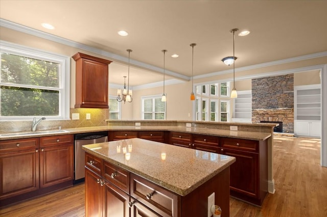 10565 Highgate Manor Ct, Duluth, GA 30097 - kitchen with stainless steel dishwasher, a kitchen island, a fireplace, wood finished floors, and light stone countertops