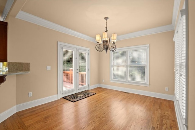 10565 Highgate Manor Ct, Duluth, GA 30097 - unfurnished dining area featuring crown molding, a chandelier, healthy amount of natural light, wood finished floors, and french doors