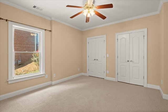 10565 Highgate Manor Ct, Duluth, GA 30097 - unfurnished bedroom featuring multiple closets, light colored carpet, ornamental molding, and ceiling fan