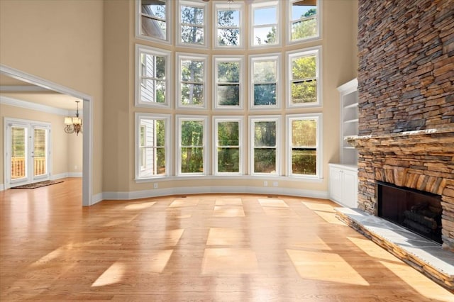 10565 Highgate Manor Ct, Duluth, GA 30097 - unfurnished living room featuring a towering ceiling, a fireplace, a chandelier, light wood finished floors, and crown molding