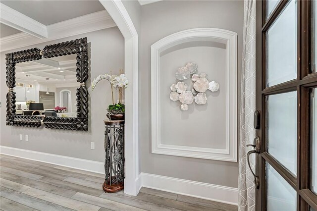 entryway with beam ceiling, light hardwood / wood-style floors, crown molding, and coffered ceiling