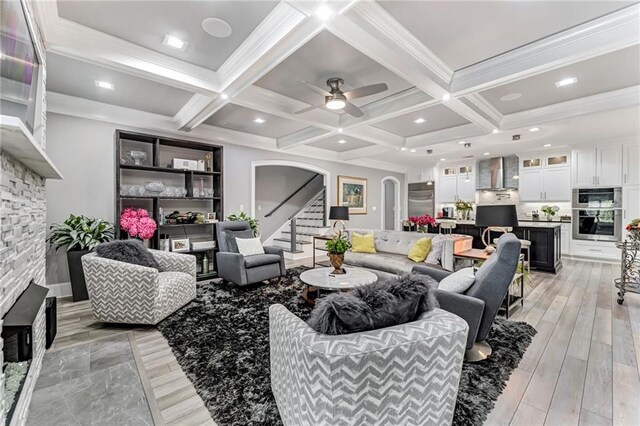 living room featuring coffered ceiling, ceiling fan, beam ceiling, and light hardwood / wood-style flooring