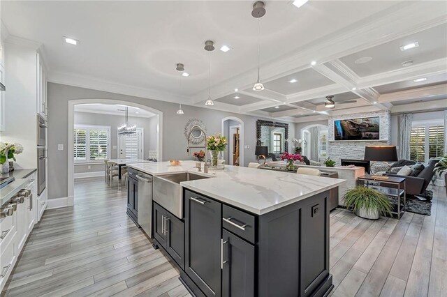 kitchen with pendant lighting, white cabinetry, an island with sink, and light hardwood / wood-style flooring