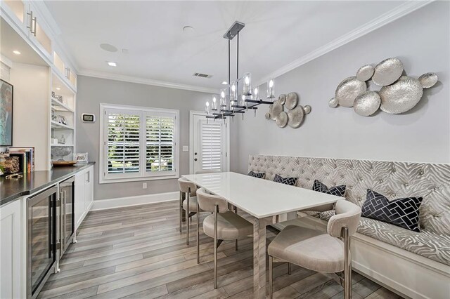 dining room featuring wine cooler, breakfast area, ornamental molding, and light hardwood / wood-style flooring