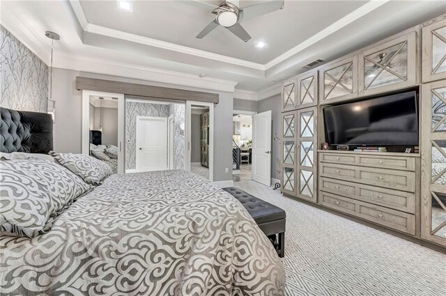 carpeted bedroom with a tray ceiling, ceiling fan, and a closet