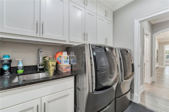 washroom featuring cabinets, washing machine and dryer, sink, and light hardwood / wood-style flooring