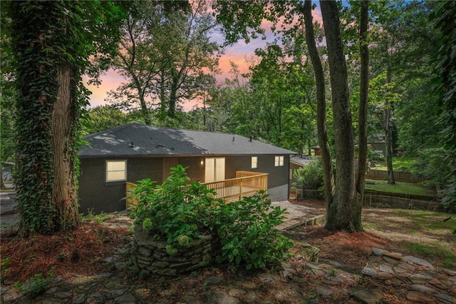 back house at dusk with a wooden deck