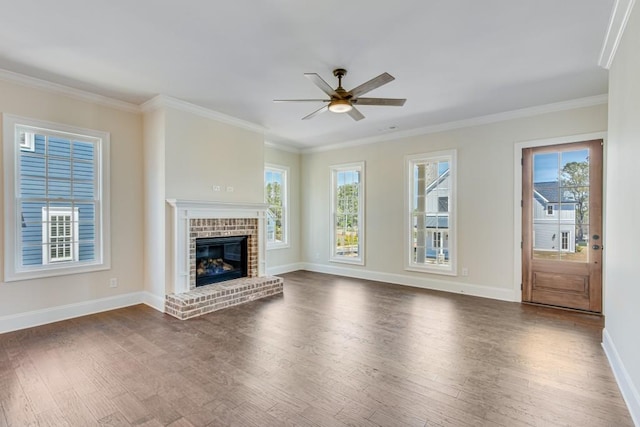 unfurnished living room with ceiling fan, ornamental molding, dark wood-type flooring, and a brick fireplace