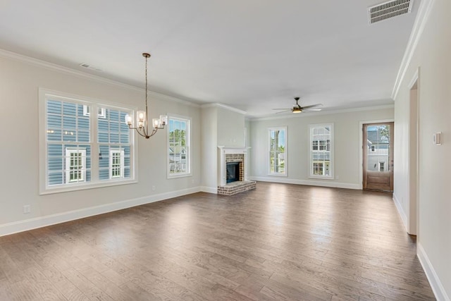 unfurnished living room featuring ceiling fan with notable chandelier, dark hardwood / wood-style floors, ornamental molding, and a brick fireplace