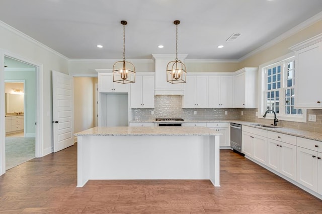 kitchen with sink, hanging light fixtures, a kitchen island, light stone counters, and white cabinets