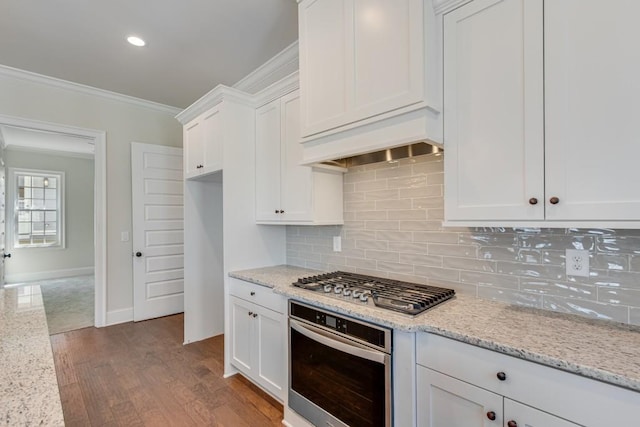 kitchen with light stone counters, white cabinets, ornamental molding, and appliances with stainless steel finishes