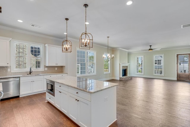 kitchen with light stone countertops, stainless steel appliances, ceiling fan, sink, and white cabinetry