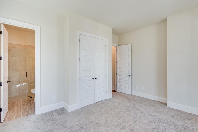 unfurnished bedroom featuring light colored carpet and ensuite bath