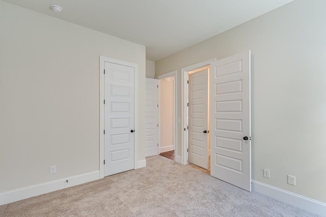 unfurnished bedroom with a closet and light colored carpet