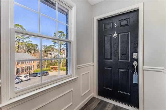 entrance foyer with dark wood finished floors, a wainscoted wall, and a decorative wall