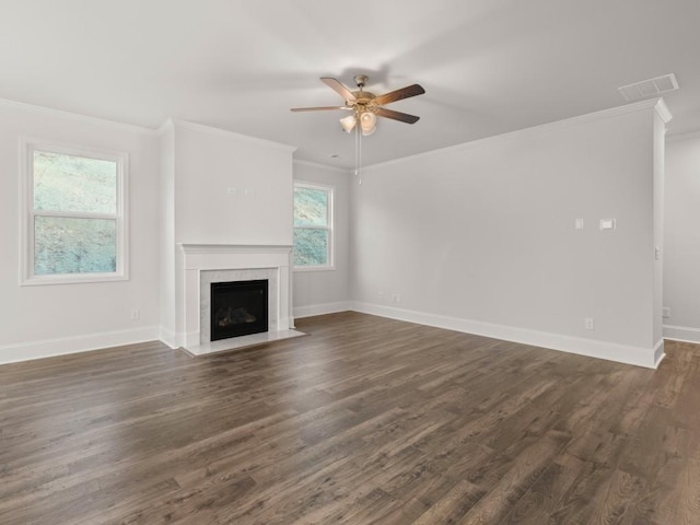 unfurnished living room featuring dark wood-type flooring, a premium fireplace, crown molding, and a healthy amount of sunlight