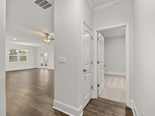 hallway featuring an inviting chandelier, dark hardwood / wood-style floors, and crown molding