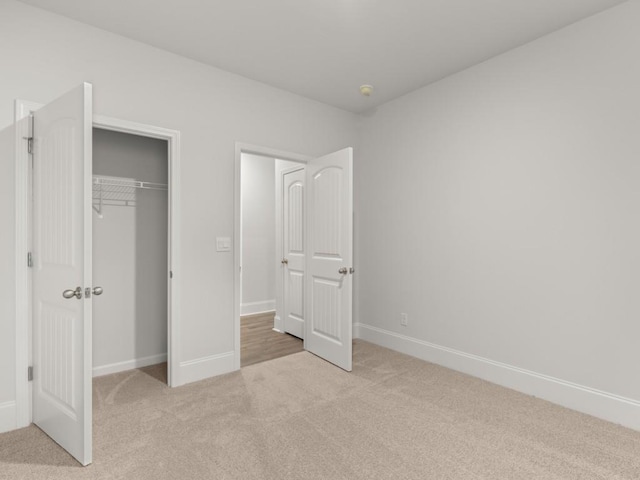 unfurnished bedroom featuring light carpet and a closet