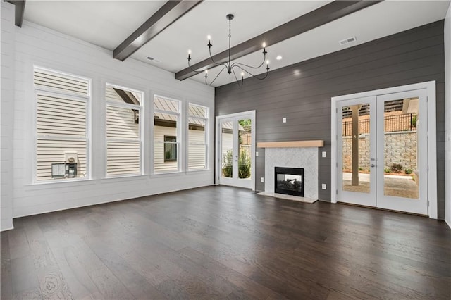 unfurnished living room with visible vents, a multi sided fireplace, beamed ceiling, french doors, and wood finished floors