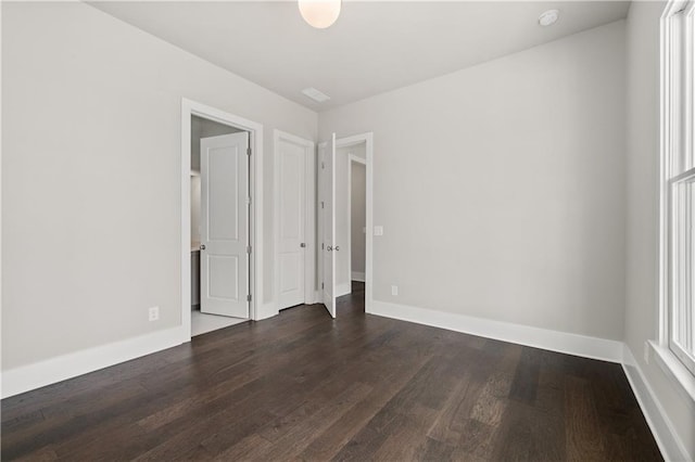 spare room featuring dark wood-style floors and baseboards