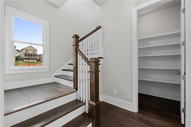 staircase featuring wood finished floors and baseboards