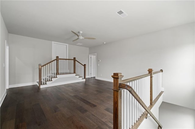 empty room featuring dark wood finished floors, visible vents, baseboards, and ceiling fan