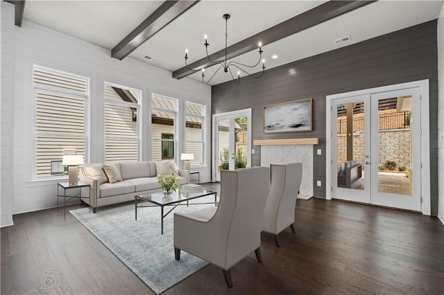 living area featuring wood finished floors, visible vents, an inviting chandelier, beam ceiling, and french doors