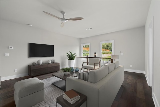 living area with dark wood-type flooring, a ceiling fan, visible vents, and baseboards