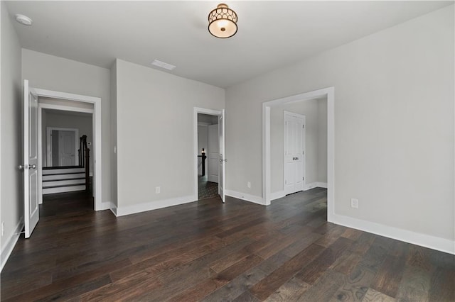 unfurnished bedroom featuring visible vents, baseboards, and dark wood-type flooring