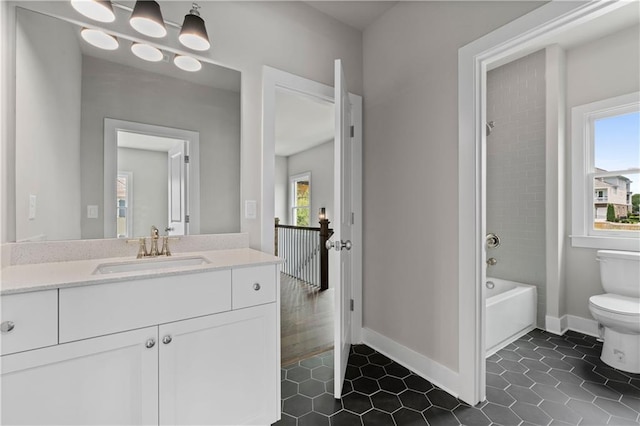 bathroom featuring vanity, toilet, a healthy amount of sunlight, and baseboards