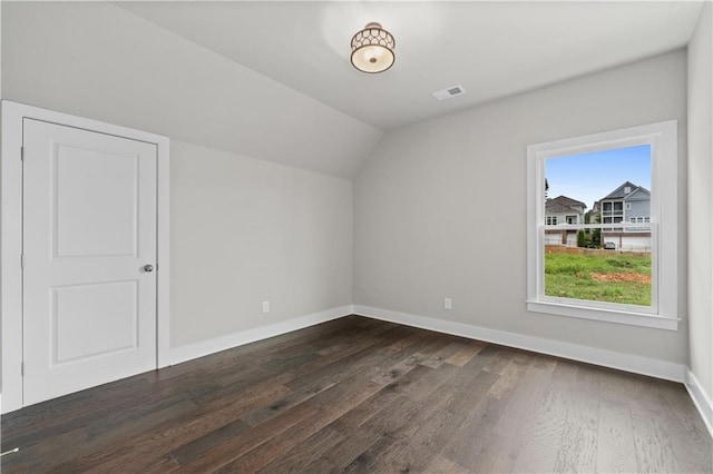 additional living space with visible vents, baseboards, dark wood-type flooring, and lofted ceiling