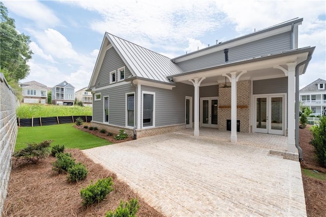 back of house featuring a standing seam roof, fence, french doors, a yard, and metal roof