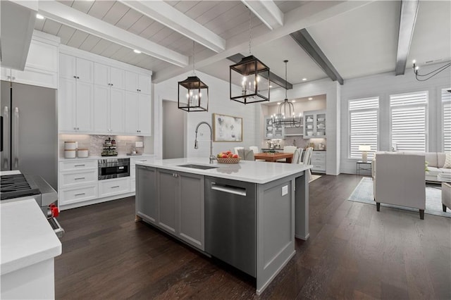 kitchen featuring a sink, open floor plan, appliances with stainless steel finishes, light countertops, and decorative backsplash